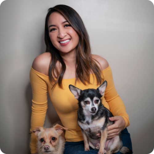 Smiling woman in yellow off-shoulder top holding two small dogs, emphasizing bridal hairstyle tips and accessories.