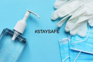 Hand sanitizer, disposable gloves, and blue face masks on a blue background with the hashtag #STAYSAFE, emphasizing health and safety during events.