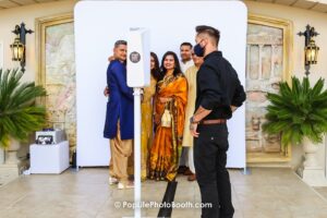 group posing in front of photo booth with clean white backdrop at wedding venue