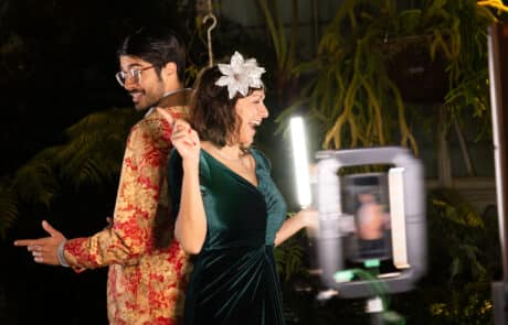 Booth visitors posing with props and ring light at a vibrant themed party.