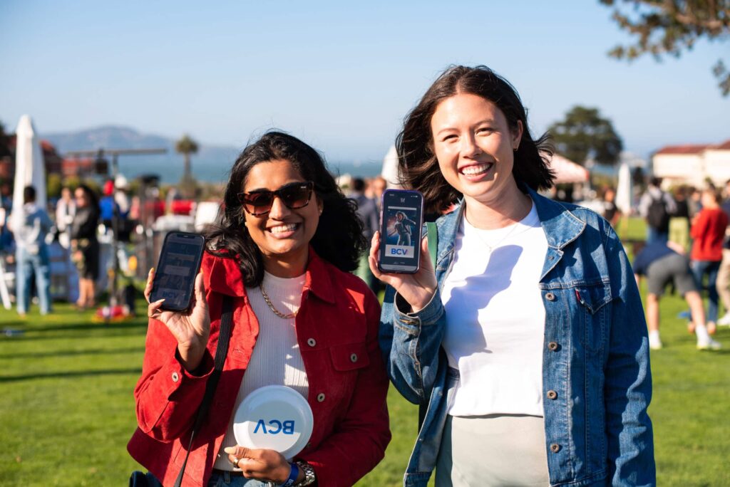 Two smiling women posing in front of roaming AI photo booth