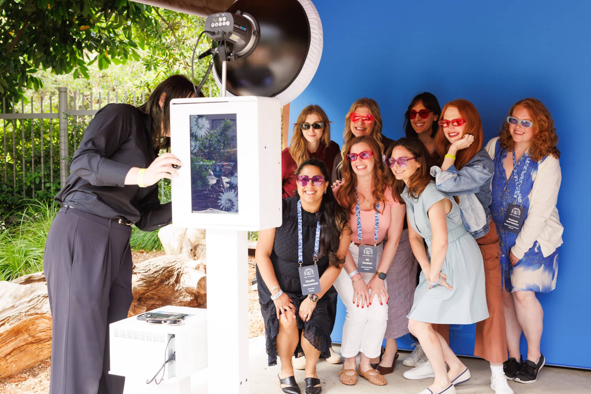 Branded photo booth with attendant and group of attendees at corporate event, professional lighting and