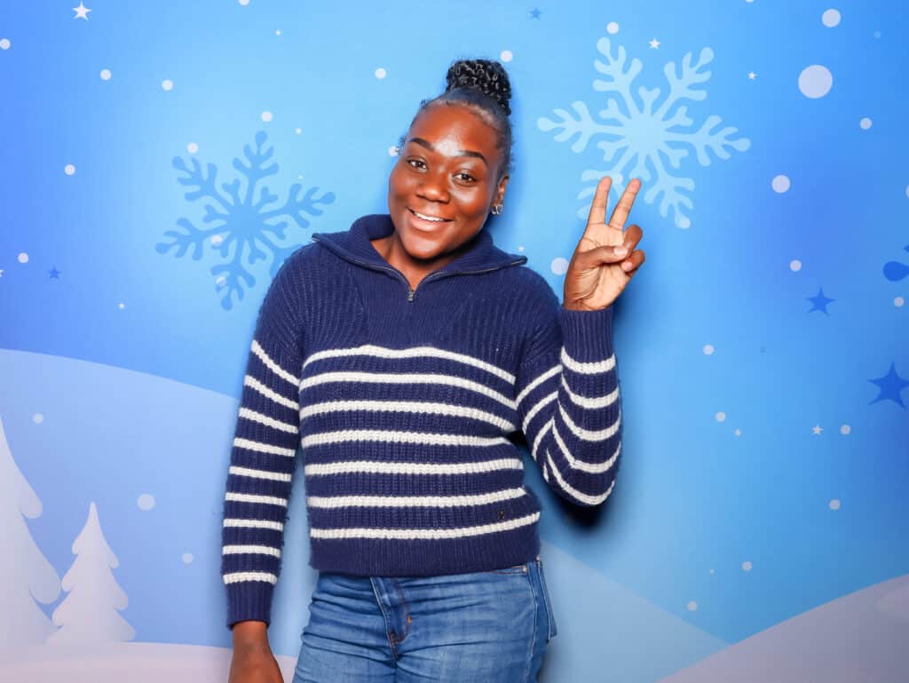 Person posing with winter holiday photo booth backdrop and festive snowflake design