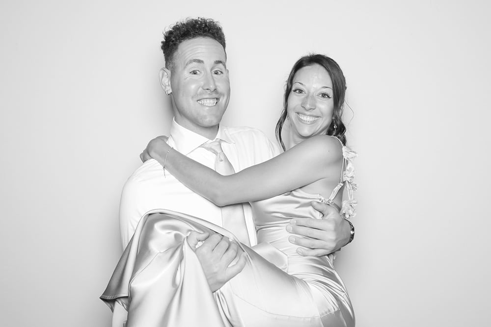 Couple joyfully posing in a playful lift, showcasing a candid and romantic moment, perfect for capturing love and connection in a photo booth setting.