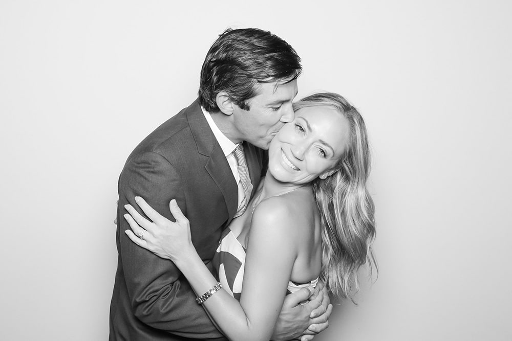 Couple sharing a tender kiss in a playful, romantic pose, embodying timeless love and charm, perfect for photo booth moments.