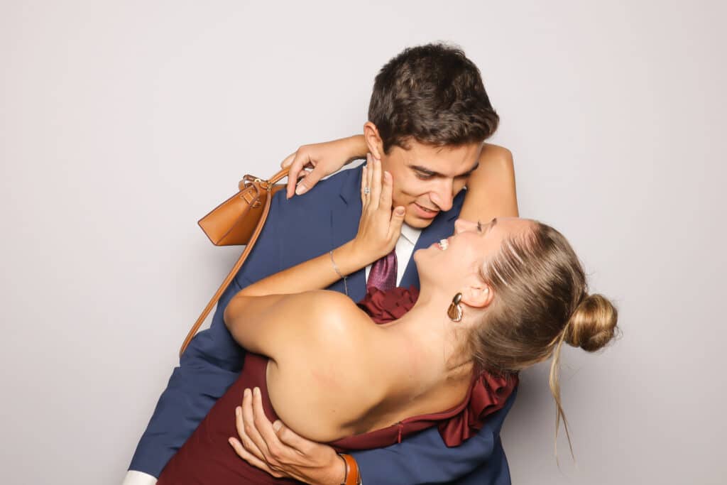 Couple sharing a romantic kiss in a playful pose, embodying sweet, candid love and joy, ideal for memorable photo booth moments.