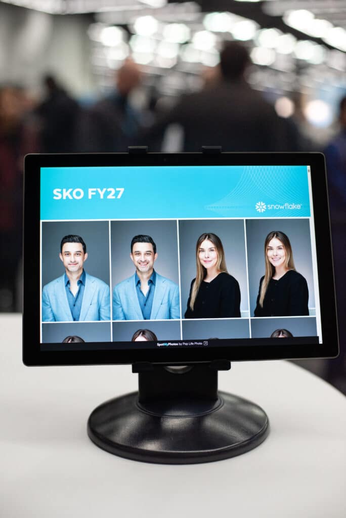 A branded digital kiosk displaying the Snowflake SKO FY27 logo and a grid of professional headshots taken during the event.