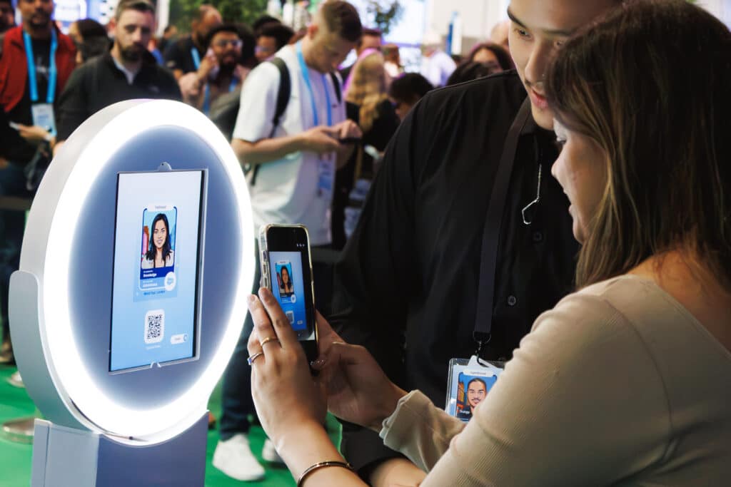 Attendees interacting with branded photo booth at technology conference, instant content delivery and social sharing.