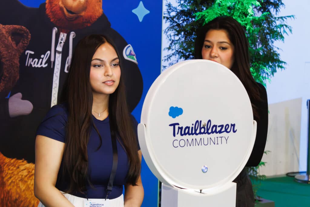 Attendee at a Salesforce Agentforce World Tour event using a round Trailblazer Community-branded photo booth, with a colorful mascot backdrop behind her.