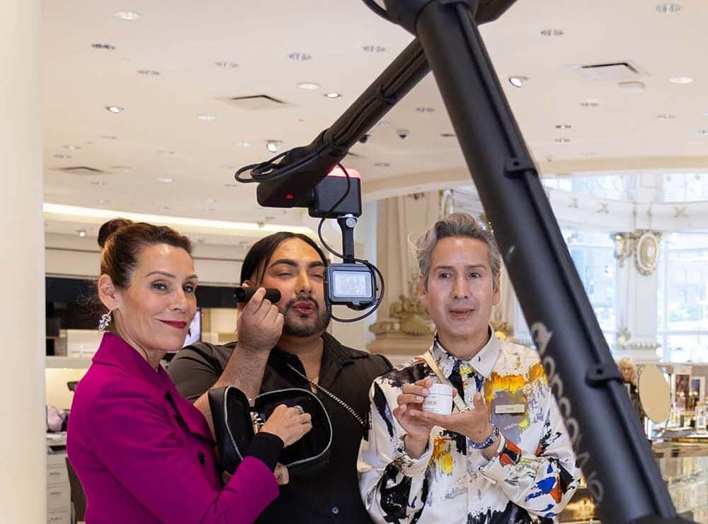 Three individuals engaging with a Glambot photo booth, showcasing a stylish setup with professional lighting, in a corporate event setting.